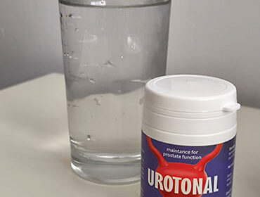 Баночка с капсулами Urotonal и стакан воды на столе.
